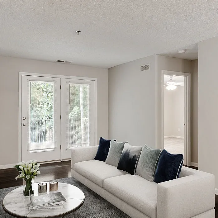 Inviting living room with elegant decor, featuring a plush sofa and modern design, opening to a private balcony with serene green views.