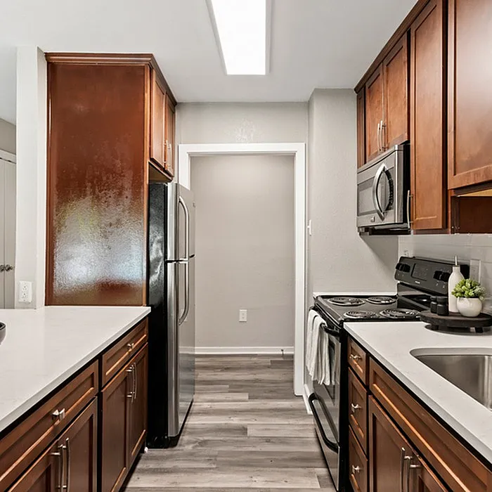 Elegant kitchen with sleek stainless steel appliances, polished wooden cabinetry, and contemporary lighting.