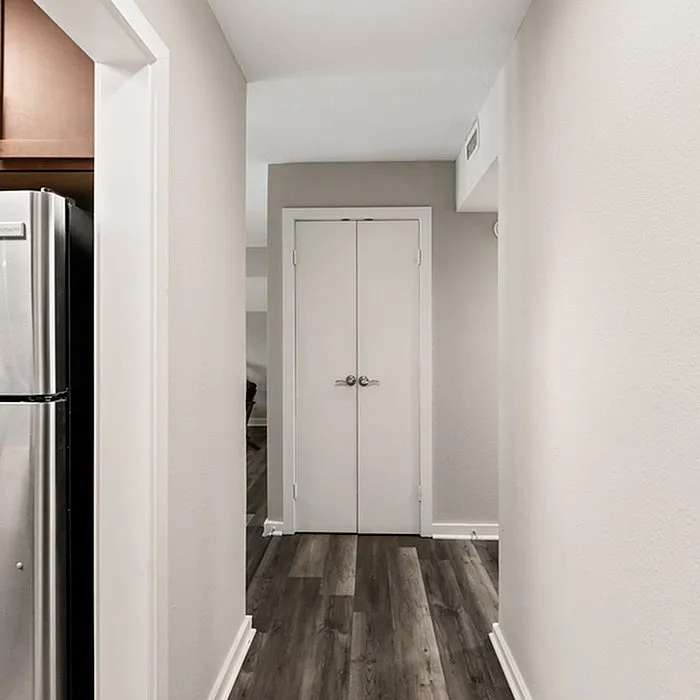 Chic apartment hallway with modern wood flooring and sleek stainless steel kitchen appliance.