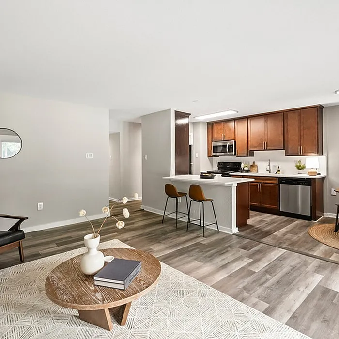 Modern open-concept apartment with sleek wooden flooring, cozy living area, and stylish kitchen with cherry wood cabinets and stainless steel appliances.