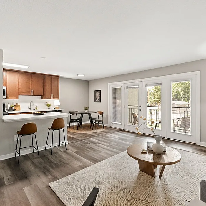 Bright and modern open-plan living area with stylish kitchen, cozy dining nook, and elegant decor, leading to a sunlit balcony.
