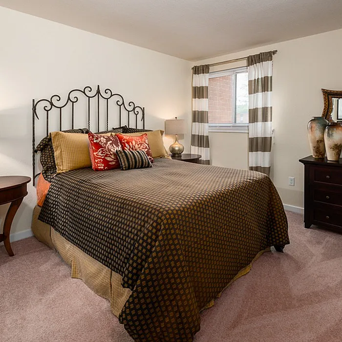 Cozy bedroom with elegant wrought iron headboard, inviting decor, and natural light from a window with striped curtains.