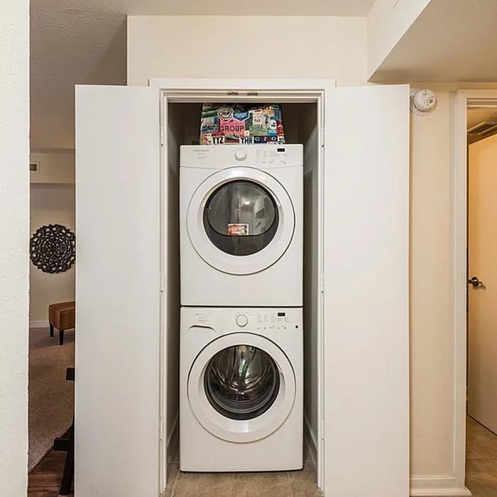 Elegant apartment features a sleek stackable washer and dryer in a compact laundry nook, offering convenience and style.