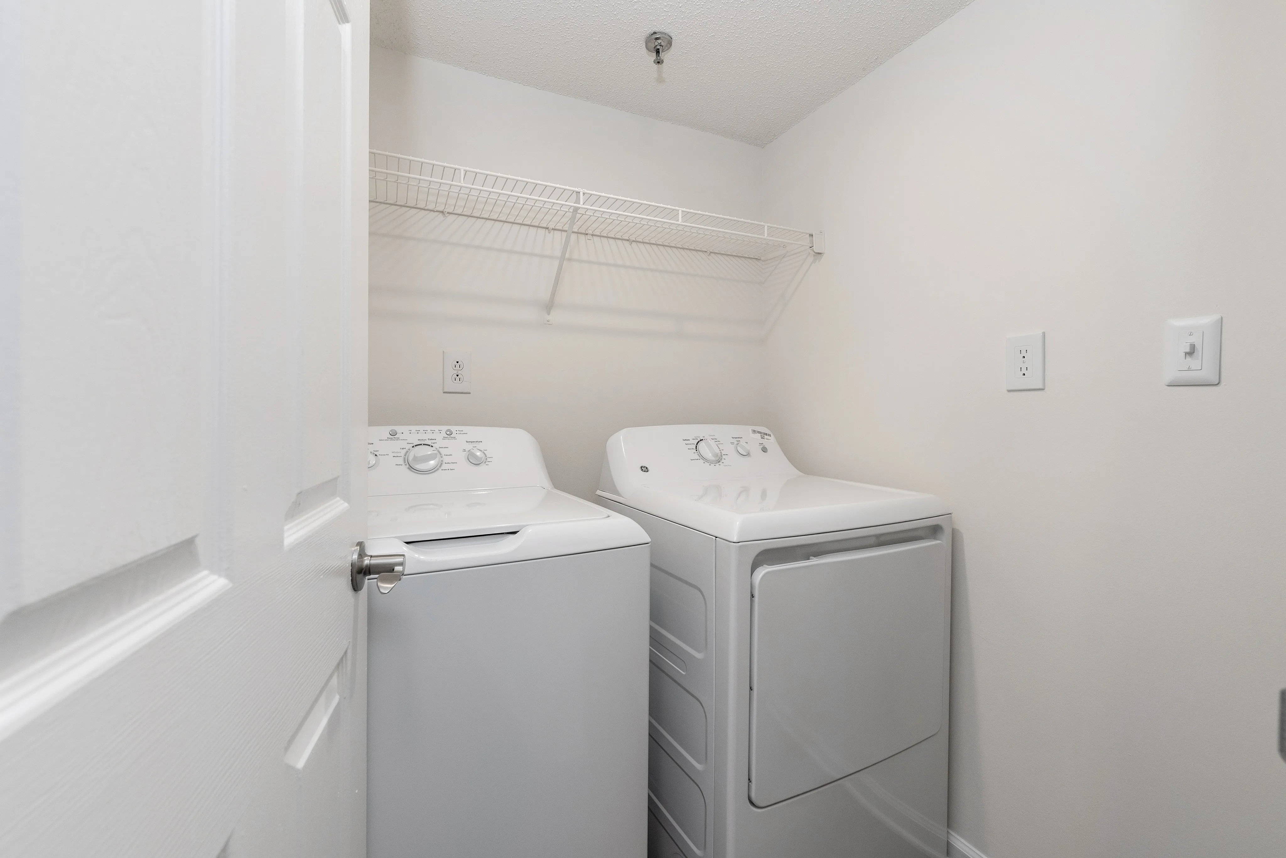 Sleek laundry room featuring modern washer and dryer set under a convenient wire shelf.