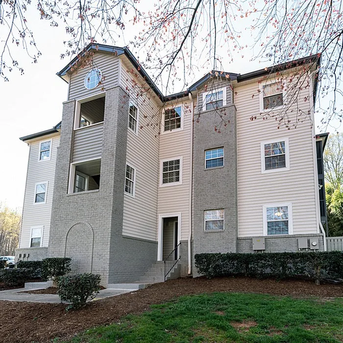 Charming modern apartment building with elegant architecture, surrounded by lush greenery, ideal for serene living.