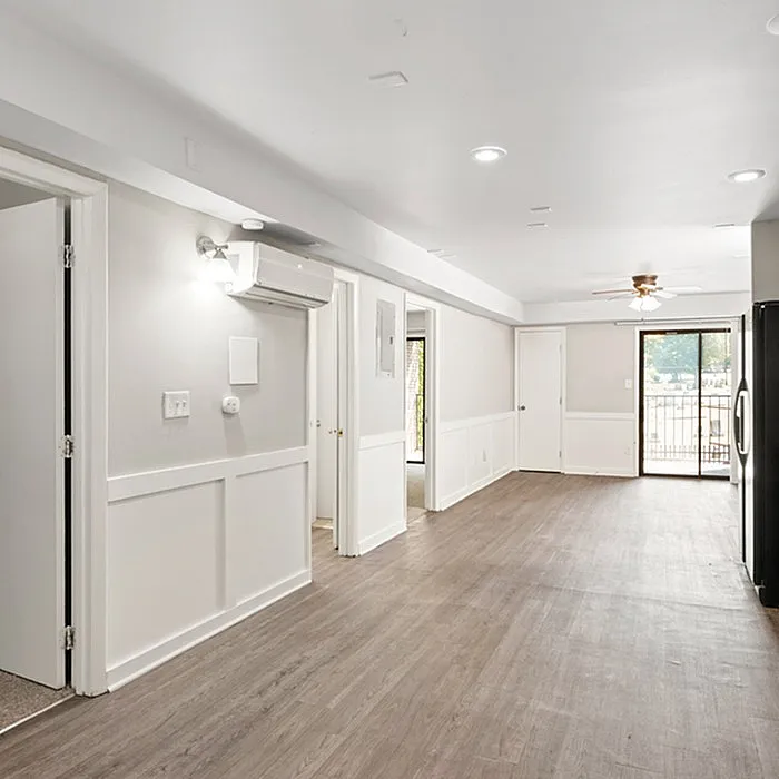 Bright open floor plan featuring elegant wood flooring, modern lighting, and a spacious layout with large sliding glass doors leading to a balcony.
