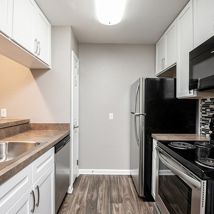 Modern kitchen with sleek stainless steel appliances, elegant cabinetry, and stylish wood flooring, perfect for culinary creations.
