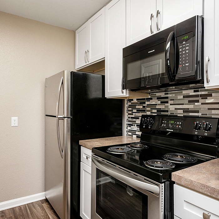Modern kitchen with sleek stainless steel appliances, stylish tile backsplash, and elegant white cabinetry.