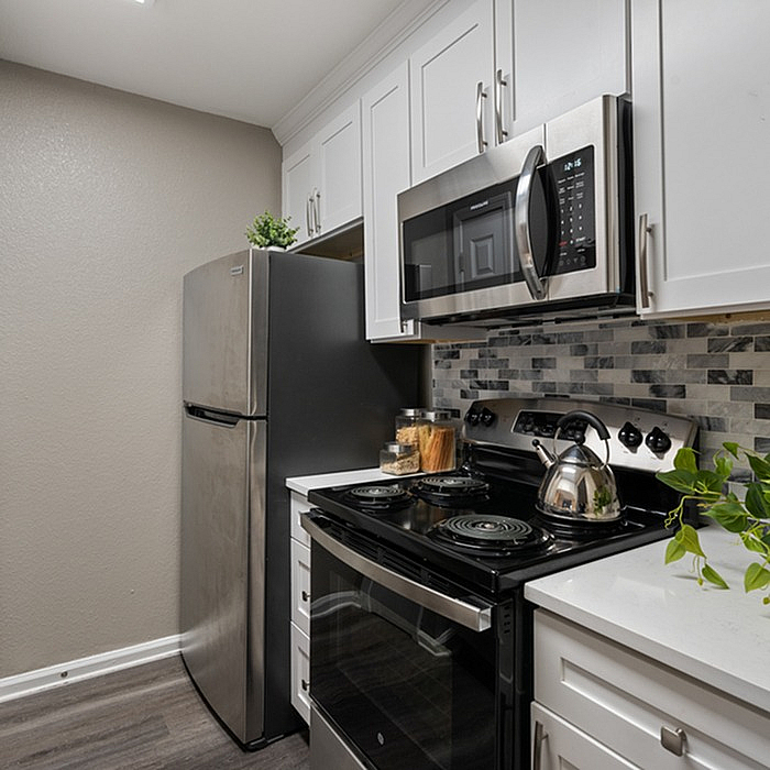 Contemporary kitchen with sleek stainless steel appliances, elegant white cabinetry, and stylish backsplash design, creating a modern and inviting cooking space.