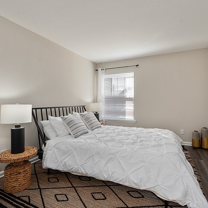 Inviting bedroom with modern decor featuring a cozy bed, elegant lighting, and a large window for natural light.