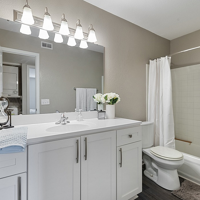 Bright and modern bathroom with elegant white cabinetry, sleek countertop, and soft lighting, offering a luxurious experience.