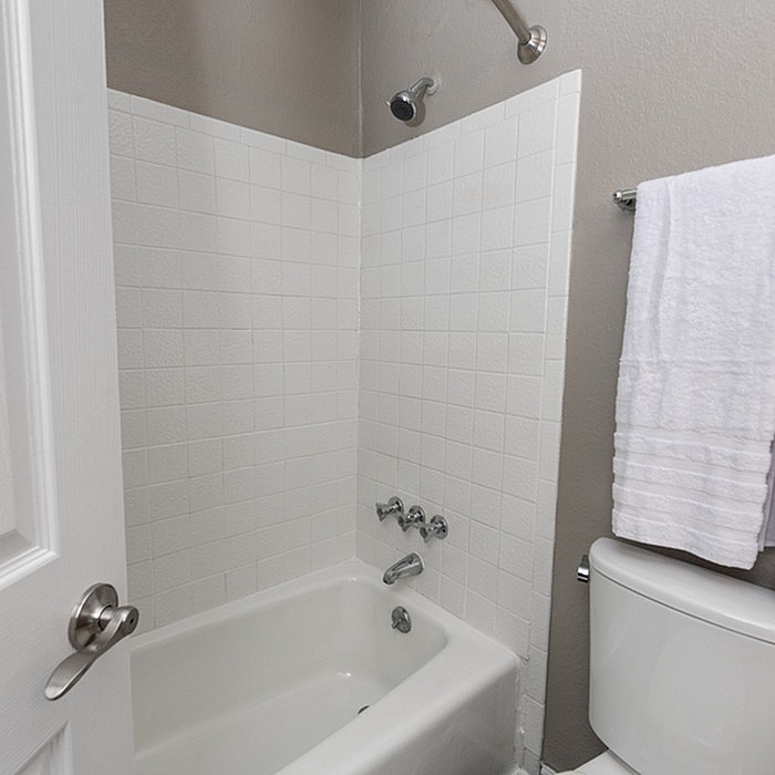 Modern bathroom featuring a pristine white bathtub, elegant tiled walls, and a sleek towel rack.