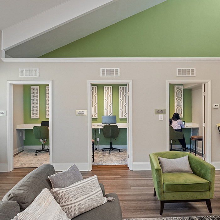 Chic apartment lounge with vibrant green accents, featuring cozy workspaces and stylish seating.