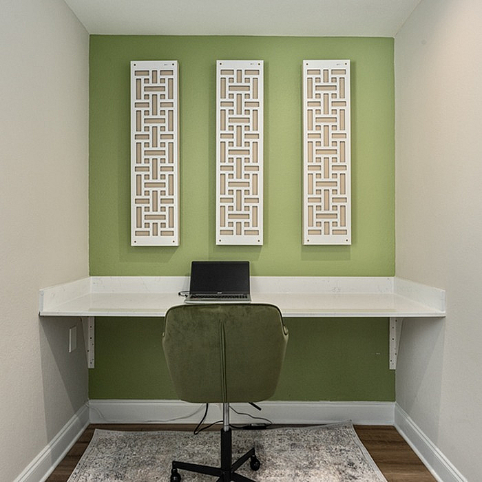 Modern home office nook with green accent wall, stylish lattice decor, and sleek workspace setup.