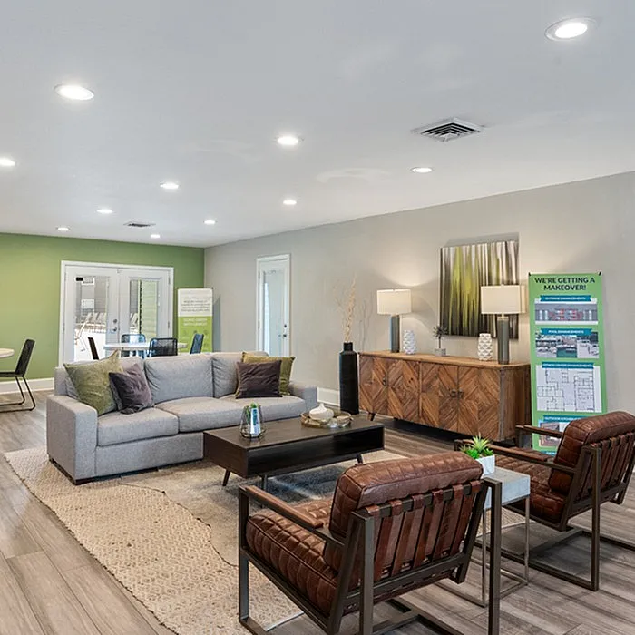 Elegant living room with modern sofa, stylish armchairs, and chic wooden sideboard, enhanced by soft ambient lighting and a fresh green accent wall.