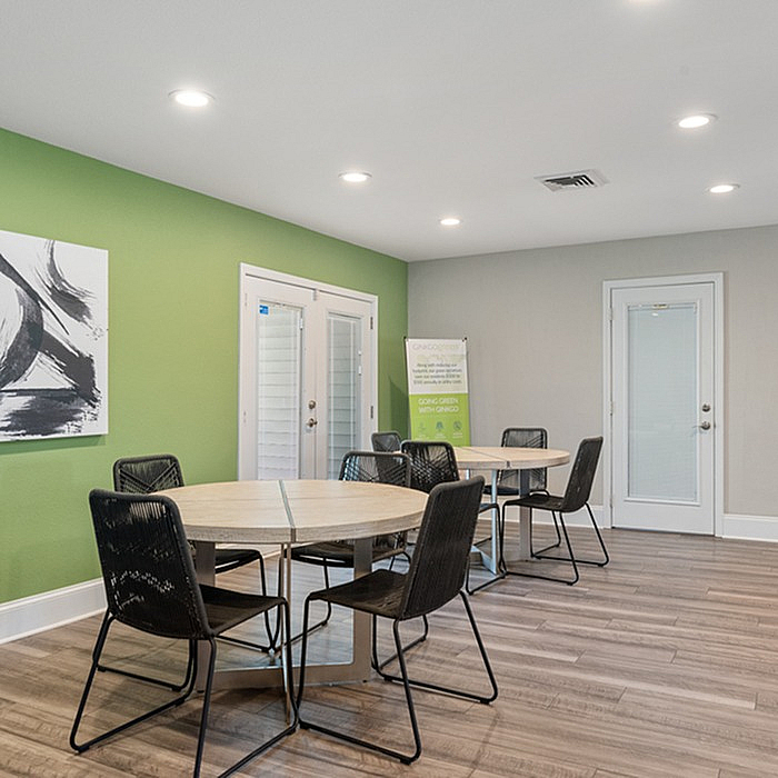 Inviting community space with bright green accent wall, modern black chairs, and round wooden tables, ideal for gatherings.