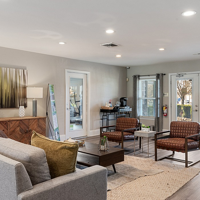 Inviting living room with modern decor, featuring a cozy gray sofa, stylish chairs, and large windows for natural light.