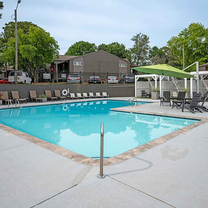 Inviting outdoor pool area with stylish lounge chairs, shaded seating, and lush greenery providing a serene retreat.