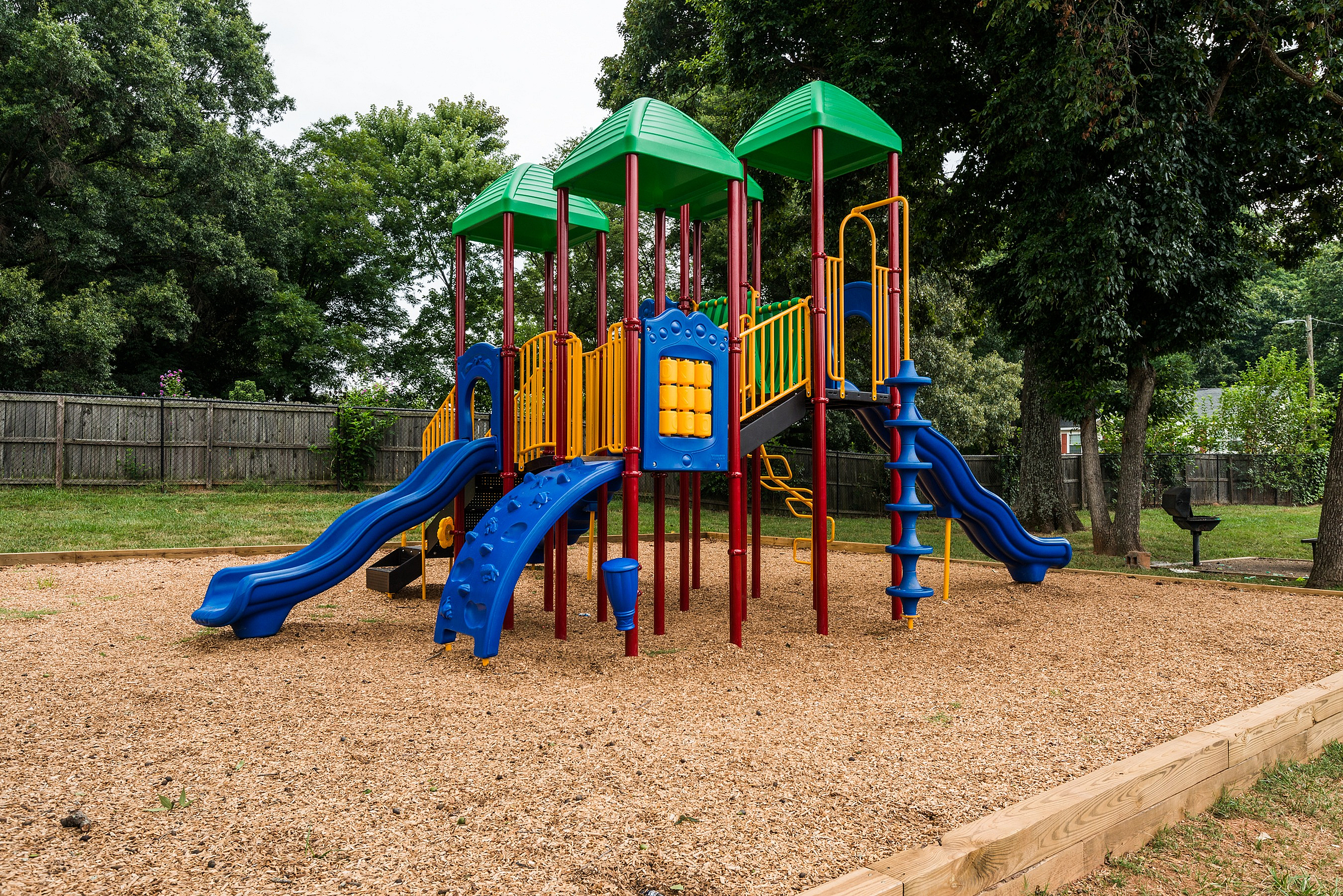 Vibrant playground featuring colorful slides and climbing structures in a lush green park setting, perfect for outdoor family fun.