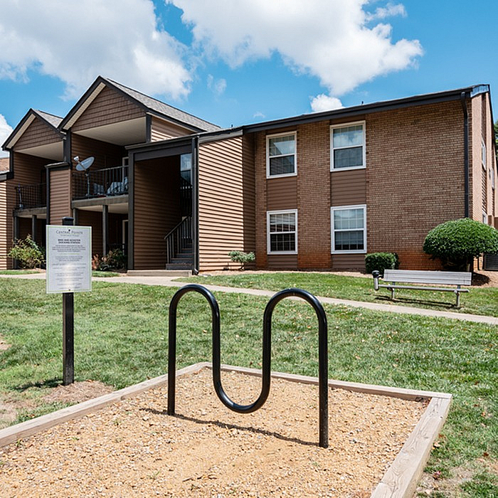 Charming apartment complex exterior with landscaped grounds, inviting pathways, and modern architecture under a bright blue sky.