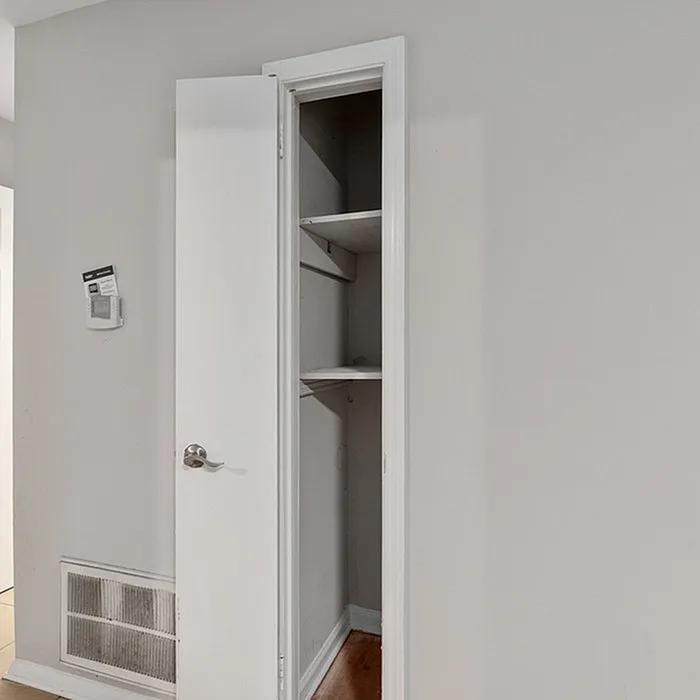 Bright and modern closet space with white door and built-in shelving offering ample storage solutions.