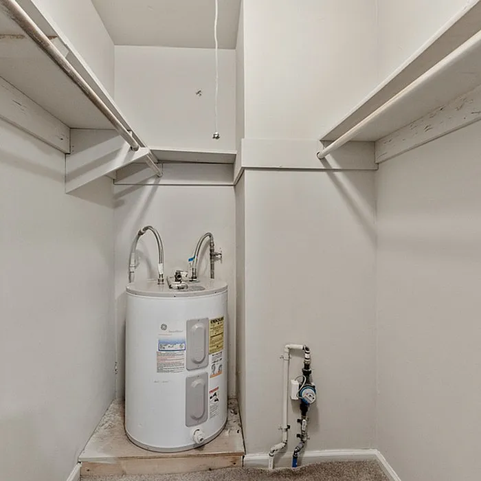 Spacious laundry room with built-in shelves and modern water heater, ideal for organizing and utility needs.