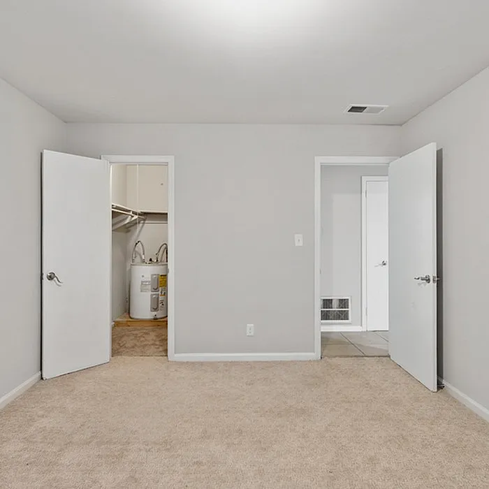 Bright, spacious room with soft carpet, featuring open doorways leading to a sleek utility room and tiled area.