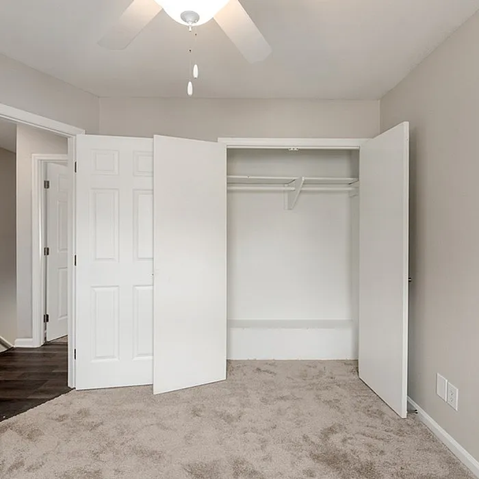 Bright and inviting bedroom with plush carpet, spacious closet, and modern ceiling fan for ultimate comfort.
