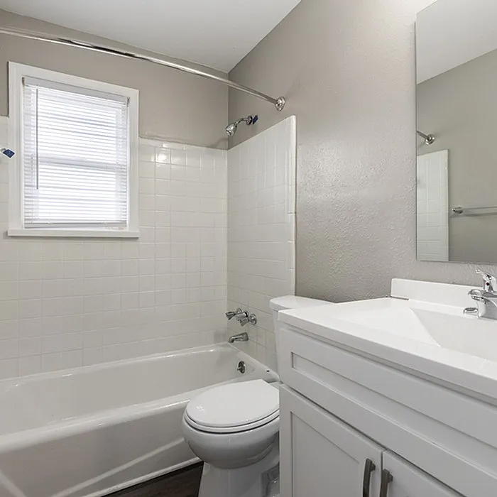 Bright and modern bathroom with sleek fixtures, a pristine white bathtub, and natural light streaming through a window.