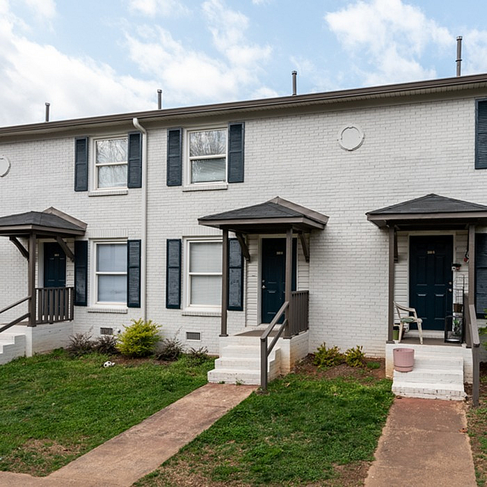 Charming brick townhouse with inviting entrance, featuring classic shutters and a cozy porch, ideal for modern living.