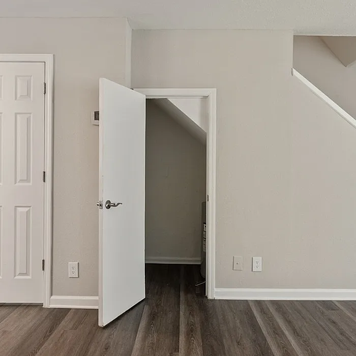 Chic minimalistic interior featuring sleek hardwood floors and a cleverly designed storage nook under the stairs.
