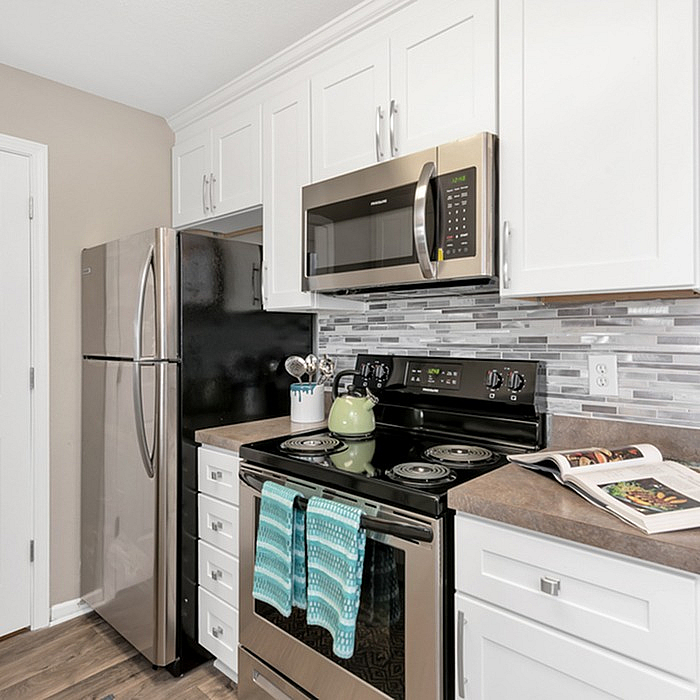 Modern kitchen with sleek stainless steel appliances, elegant white cabinetry, and stylish tiled backsplash.