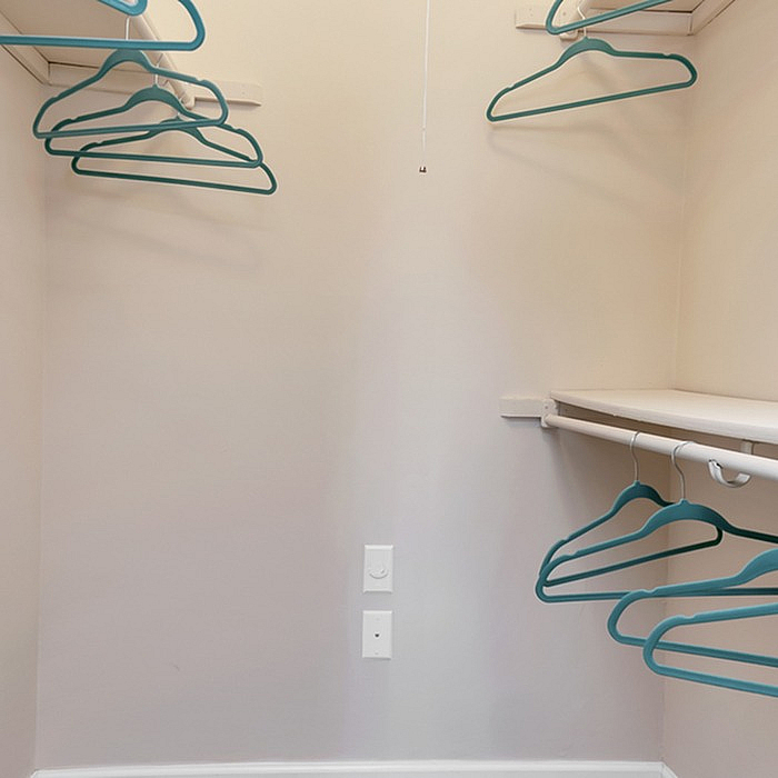 Spacious walk-in closet with modern shelving and teal hangers, offering ample storage in a stylish apartment.