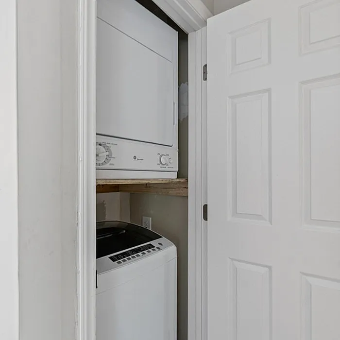 Compact, built-in laundry unit featuring a stacked washer and dryer, perfect for maximizing apartment space effectively.