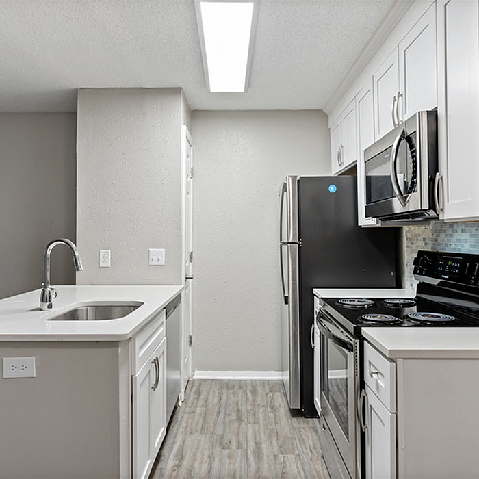 Modern kitchen with stainless steel appliances, sleek white cabinetry, and stylish tile backsplash.