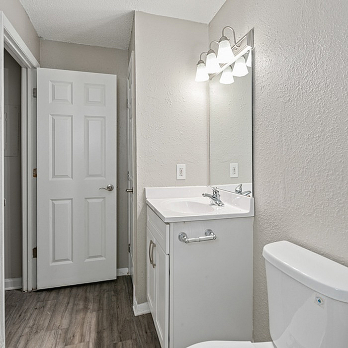 Modern bathroom in neutral tones featuring a sleek vanity with a large mirror and elegant lighting.