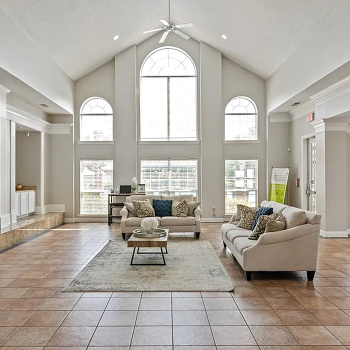 Elegant living room with high vaulted ceilings, large arched windows, and stylish sofas on a tiled floor, creating a bright and inviting atmosphere.