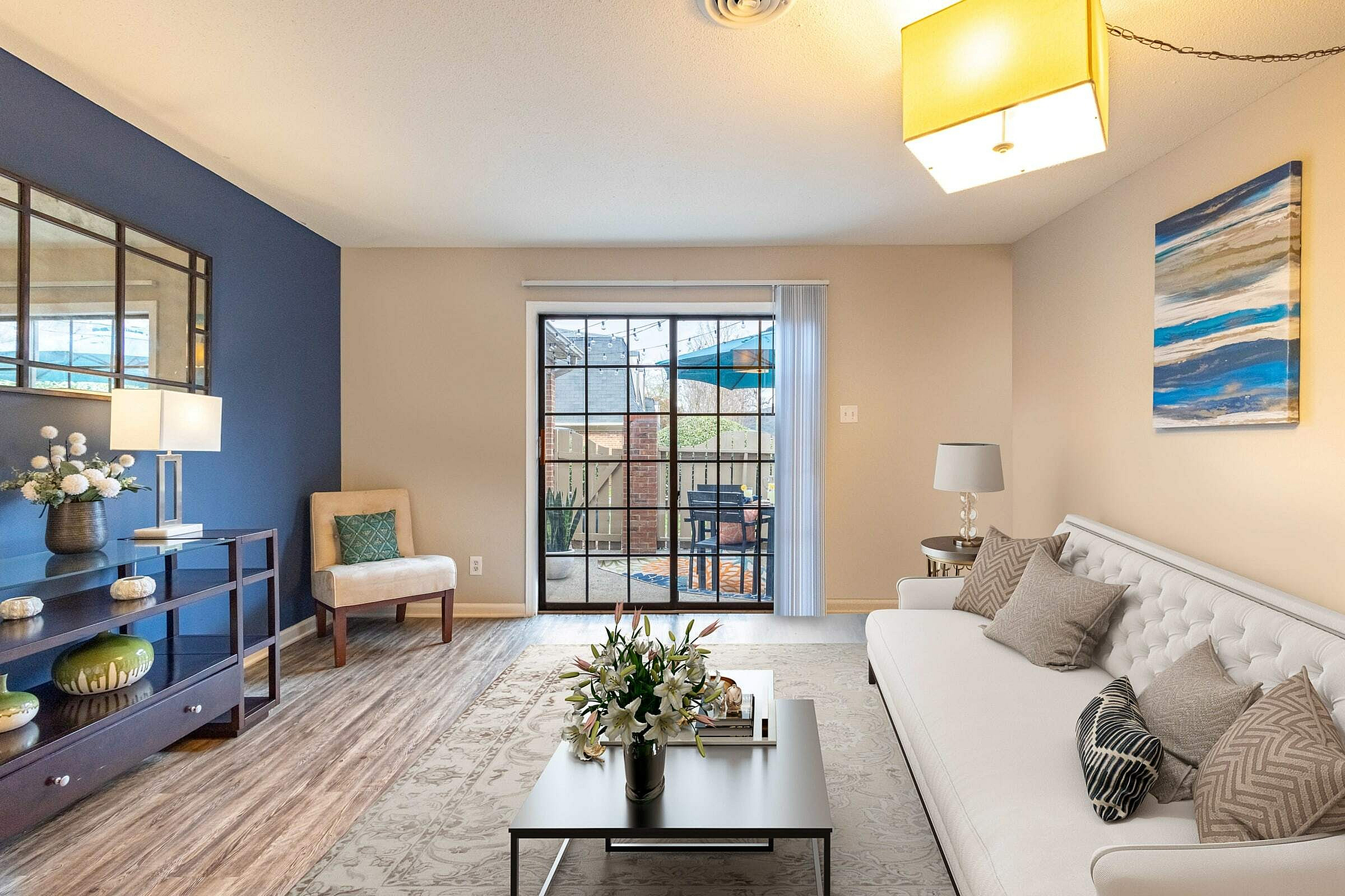 Inviting living room with elegant decor, featuring a modern white sofa, vibrant blue accent wall, and cozy patio access.