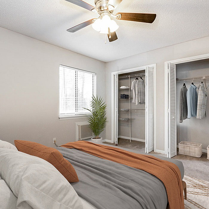 Bright and inviting bedroom with modern ceiling fan, organized closet space, and stylish decor.