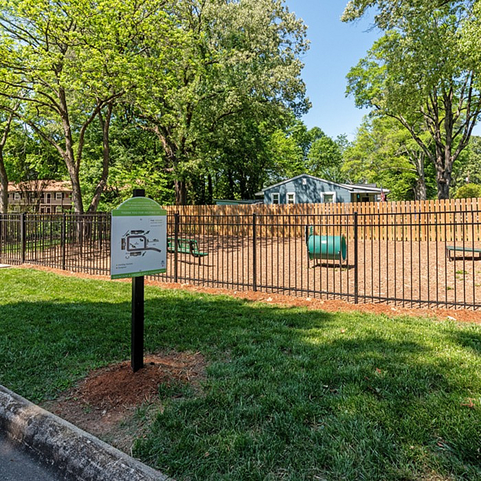 Charming fenced dog park with agility structures surrounded by lush greenery, perfect for pet-friendly apartments.