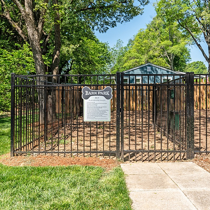 Charming dog park with secure fencing set amidst lush green trees, perfect for pet enjoyment.