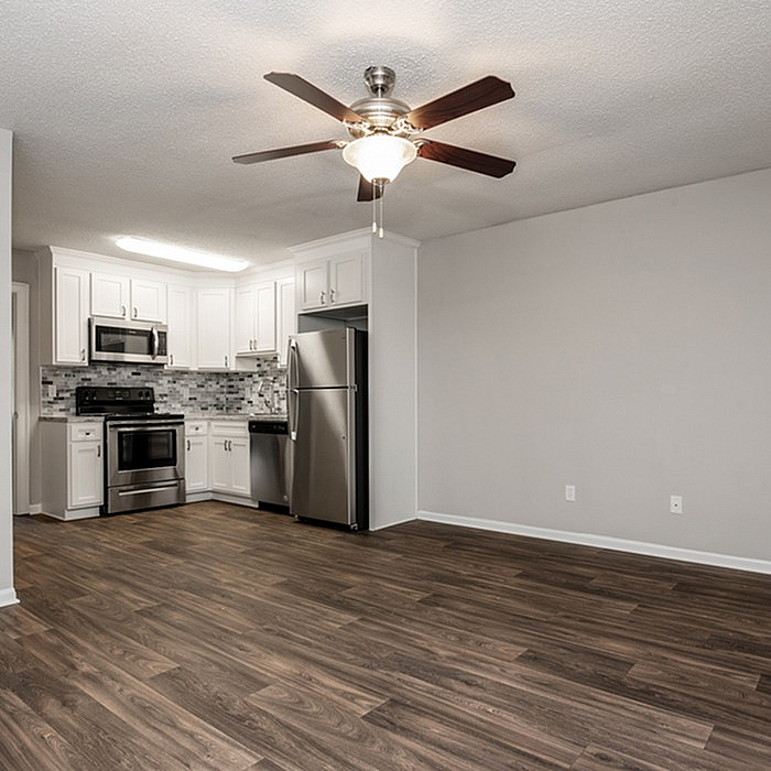Modern open-concept kitchen with stainless steel appliances, elegant white cabinetry, and sleek hardwood flooring.