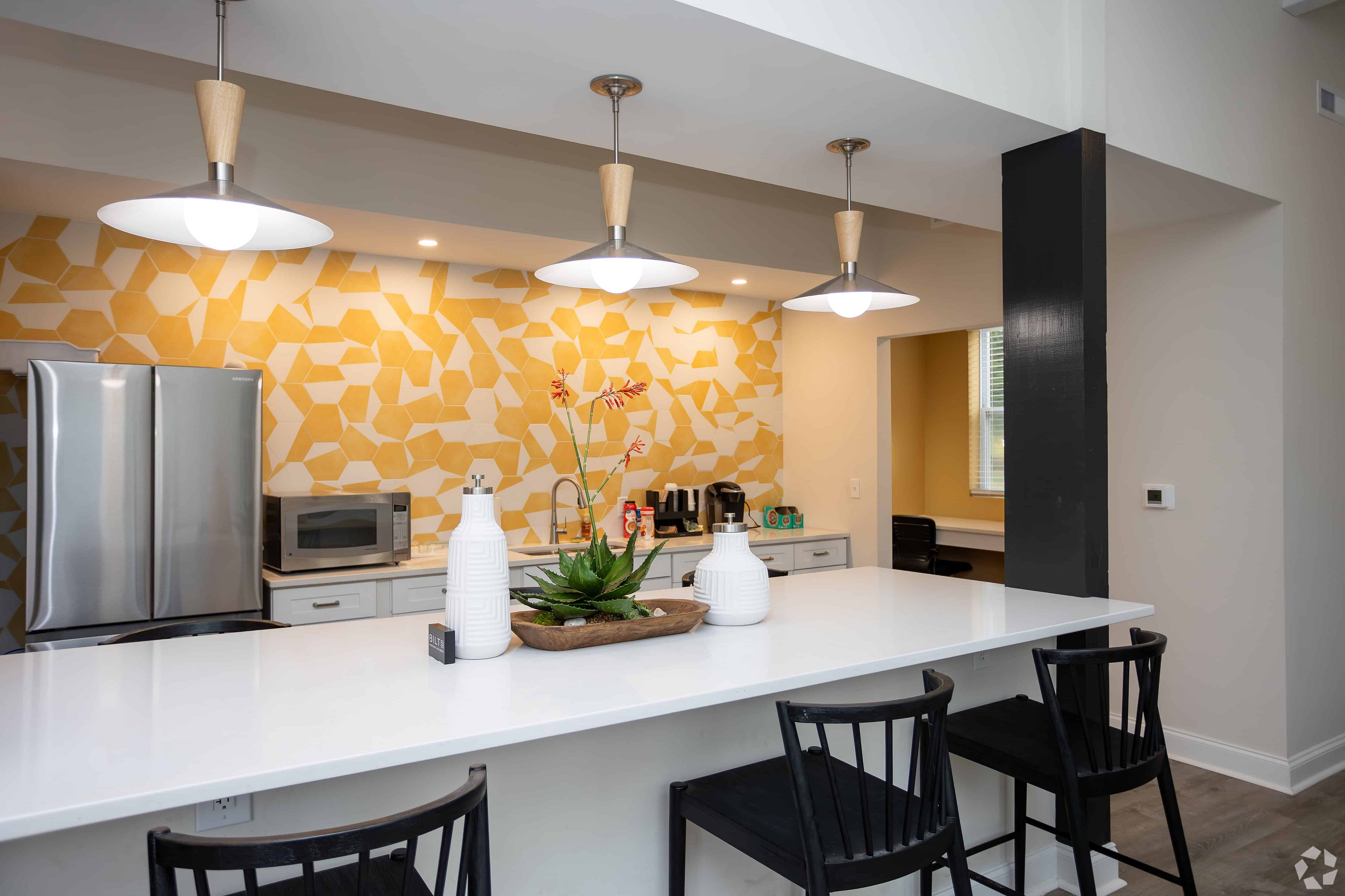 Modern kitchen with stylish pendant lighting, vibrant yellow geometric backsplash, and sleek countertops perfect for dining and entertaining.