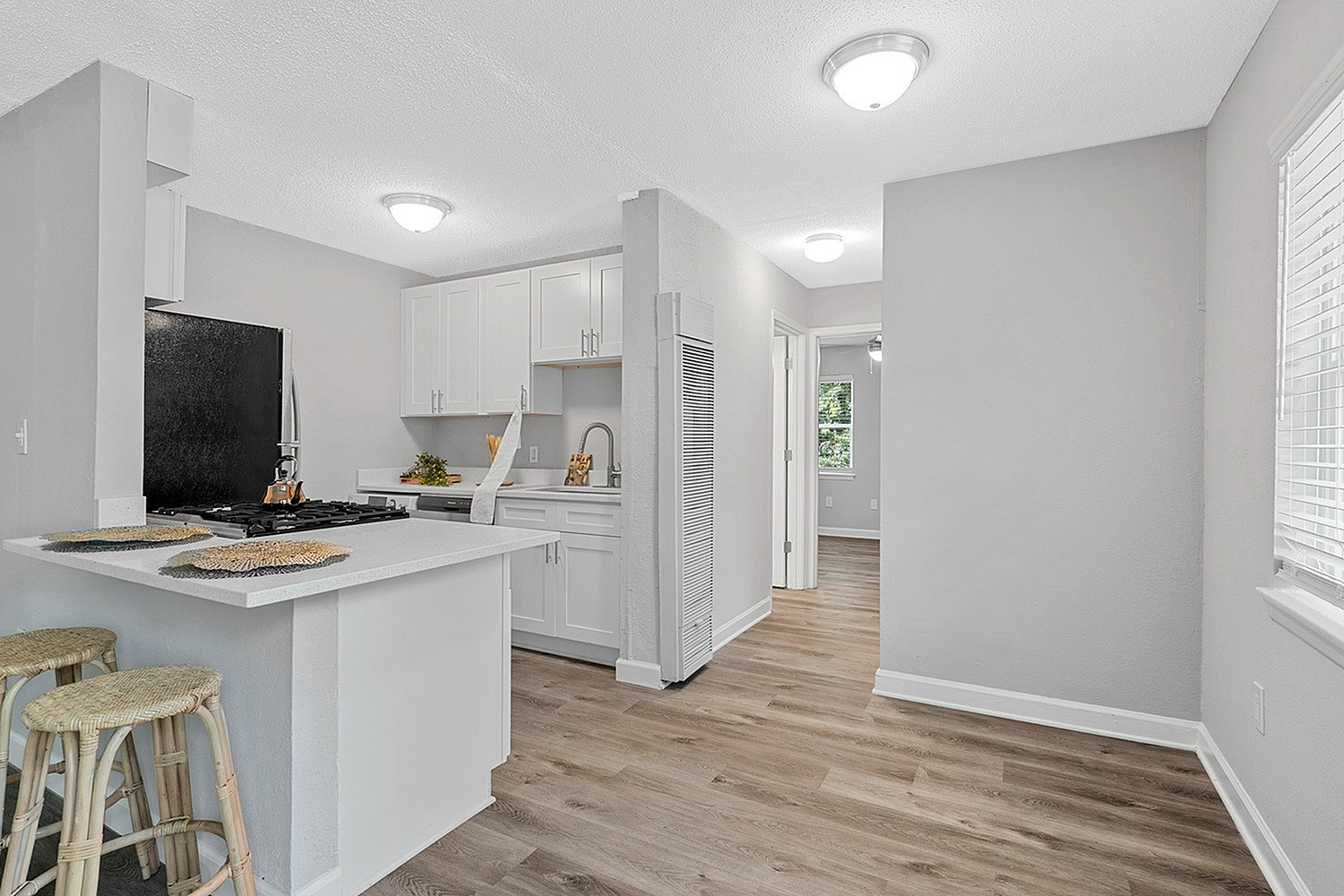 Bright and modern kitchen space with sleek white cabinets, stylish countertops, and elegant wood flooring, creating a warm and inviting atmosphere.