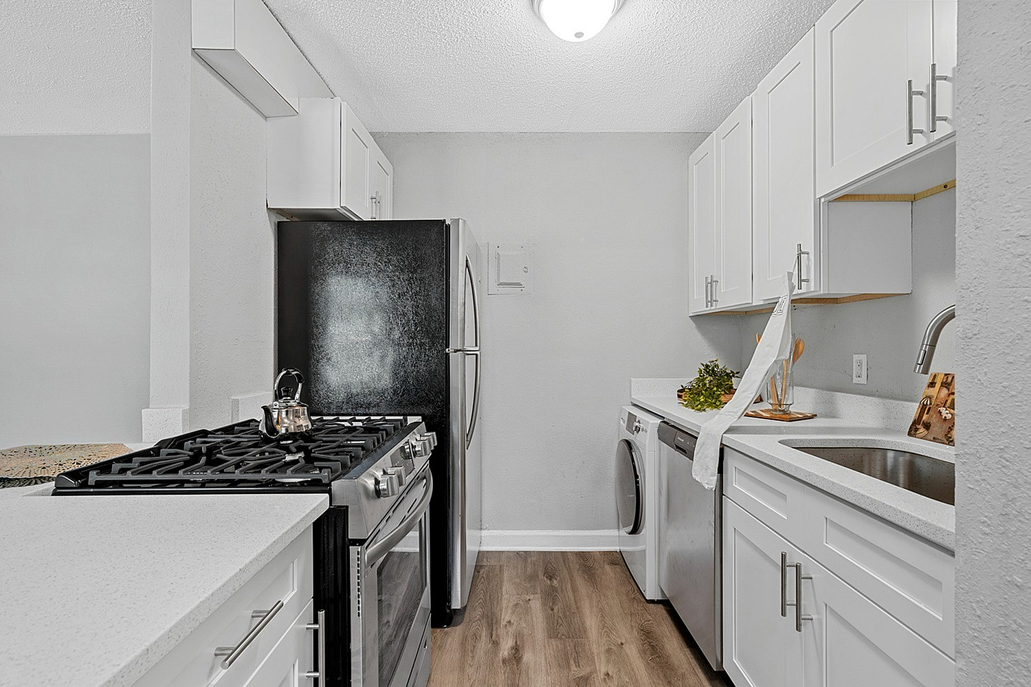 Sleek modern kitchen with stainless steel appliances, elegant white cabinetry, and stylish wood flooring.