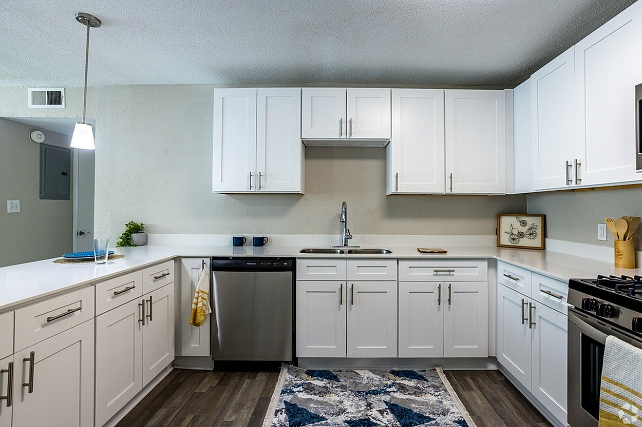 Modern kitchen with sleek white cabinets, stainless steel appliances, and stylish wood flooring, perfect for contemporary living.