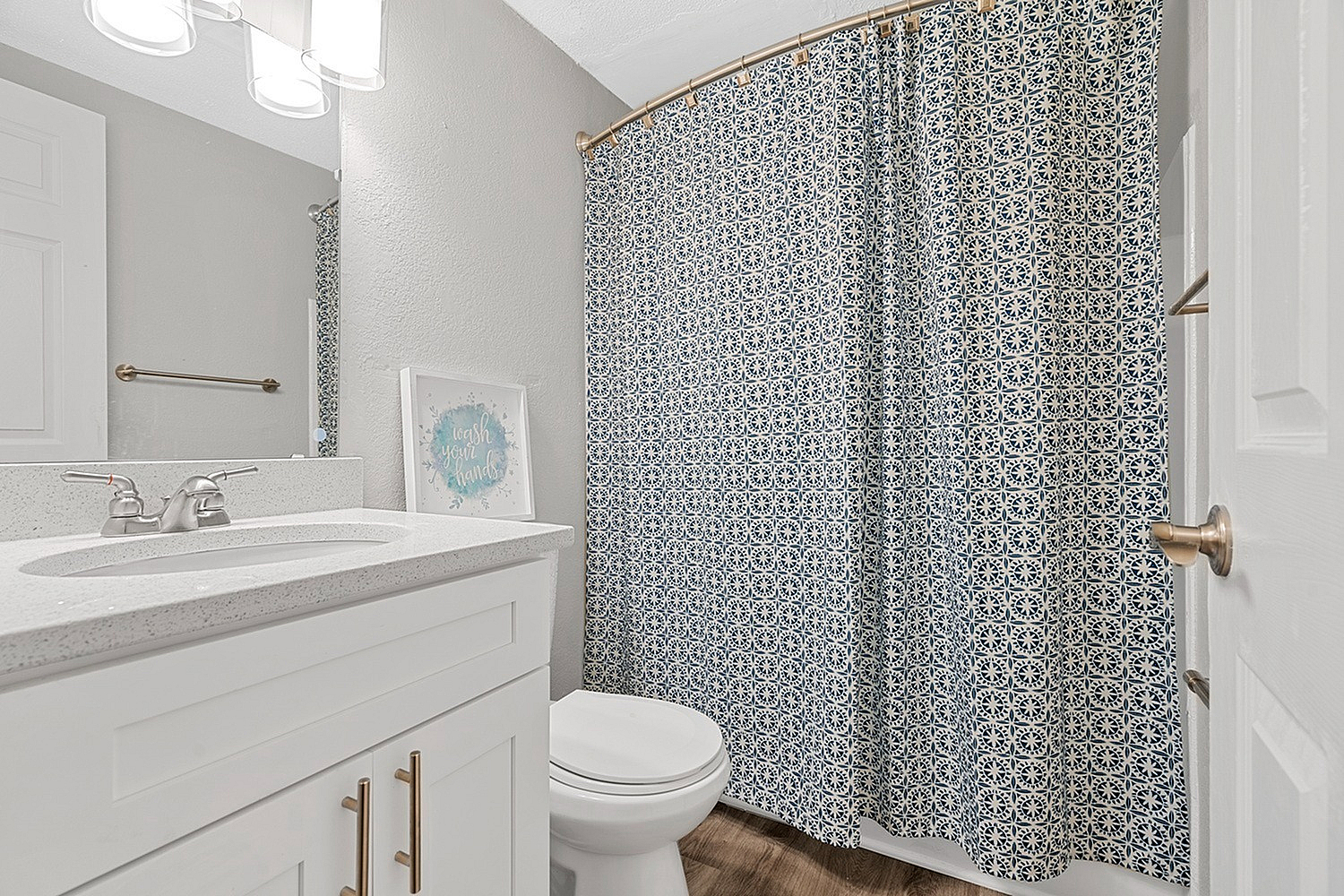Inviting bathroom featuring a modern vanity, elegant lighting, and a stylish patterned shower curtain.