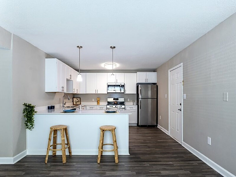 Modern kitchen with sleek cabinetry, stainless steel appliances, and a white breakfast bar with stool seating.