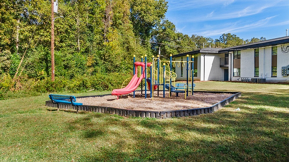 Inviting playground with colorful slides and play structures surrounded by lush greenery, perfect for family fun and outdoor activities.