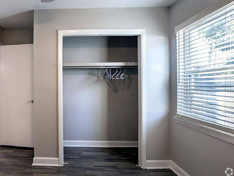 Bright and inviting empty closet space with elegant wooden flooring and large sunny window, perfect for organizing your wardrobe in style.